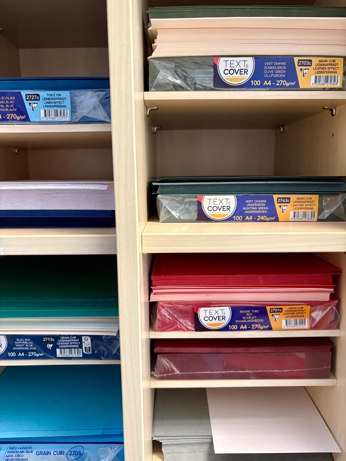 Regal mit Clairefontaine-Deckblattkarton in vielen Farben: Blau-, Grün- und Rottöne mit Leder- und Leinenprägung