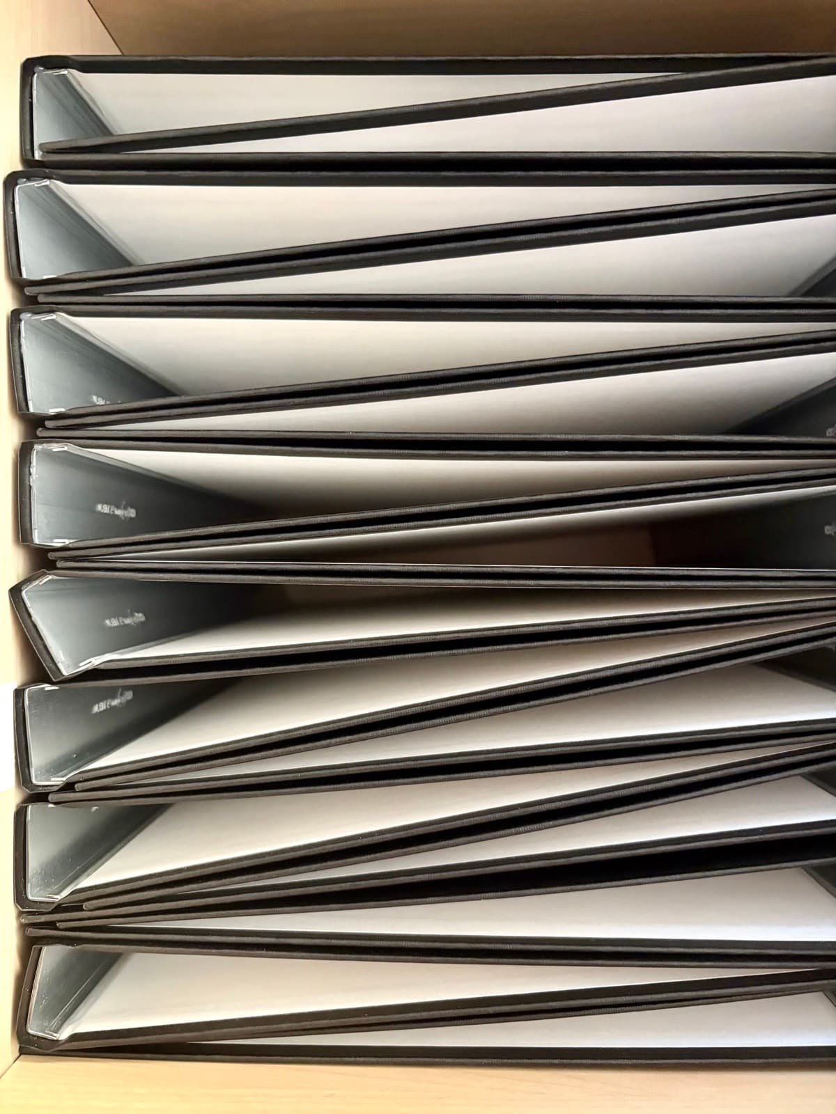 Stapel schwarzer Hardcover-Mappen in unserem Regal – bereit für die nächsten Abschlussarbeiten